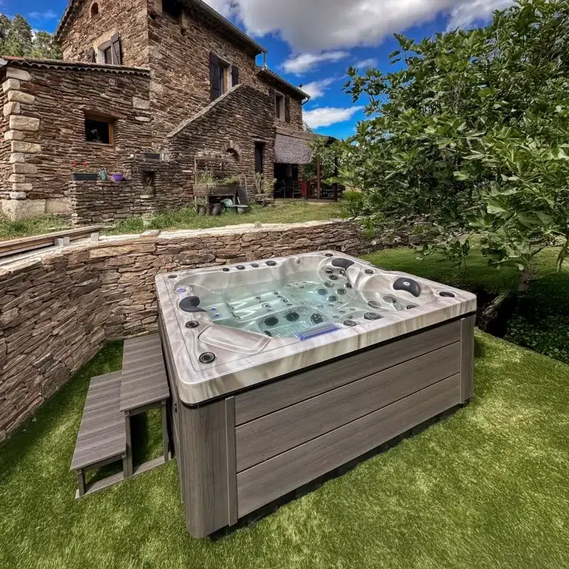 Spa Barthélemy installé dans un jardin de campagne avec pelouse et maison en pierres – Only Spa