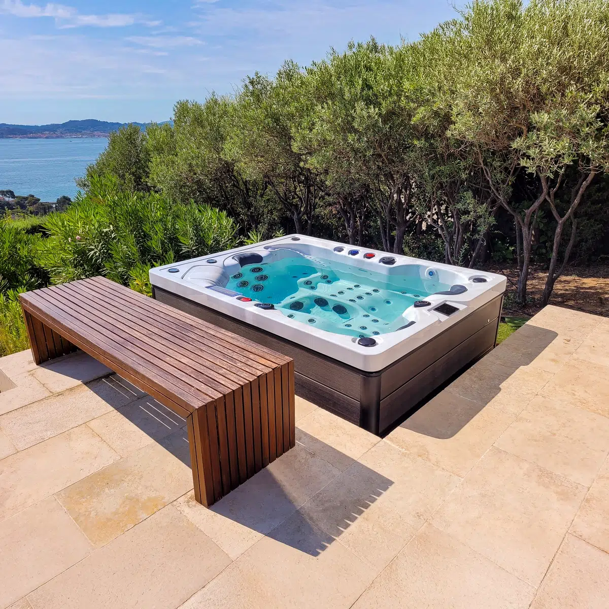 Spa Jamaïque en fonctionnement, sur une terrasse en pierre avec banc design, en harmonie avec les oliviers environnants