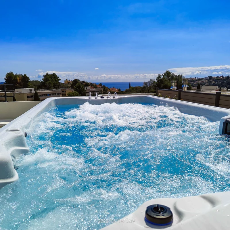 Vue rapprochée des jets en fonctionnement du spa de nage monobassin Tilos de la marque Vendom, installé dans un jardin moderne