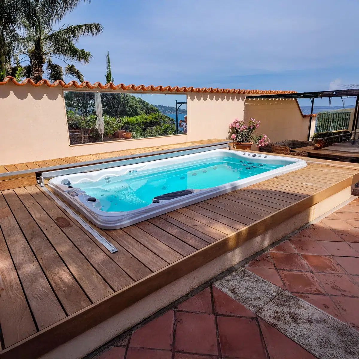 Le spa de nage Tilos de Vendom en pleine utilisation, avec jets massants activés et panorama côtier en arrière-plan