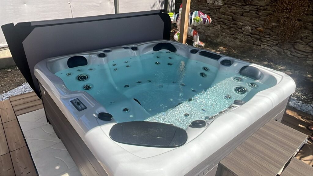 Spa sur une terrasse près d’un mur en pierre — réalisation Onlyspa